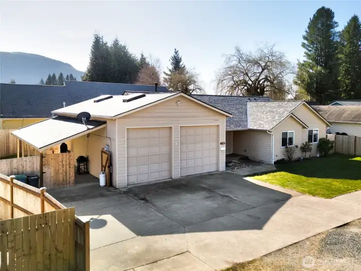 Spacious attached garage with ten foot tall garage doors and covered caport attached to side.