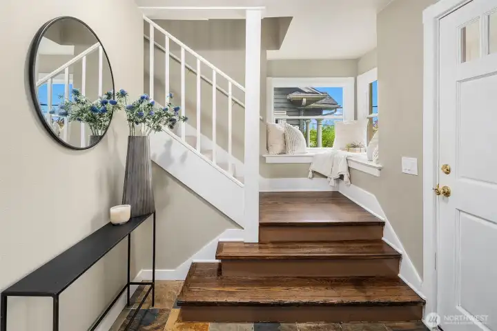 Stairwell leading to the upper level with chocolate-stained hardwoods and bench for seating. Love the big windows!