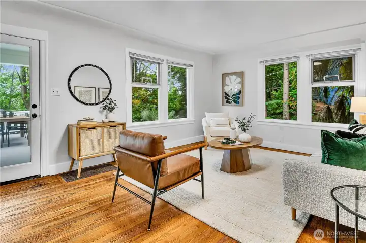 Warm and inviting living room featuring beautiful hardwood floors, expansive windows that fill the space with natural light, and a classic tiled wood-burning fireplace. Warm and inviting living room featuring beautiful hardwood floors, expansive windows that fill the space with natural light, and a classic tiled wood-burning fireplace.