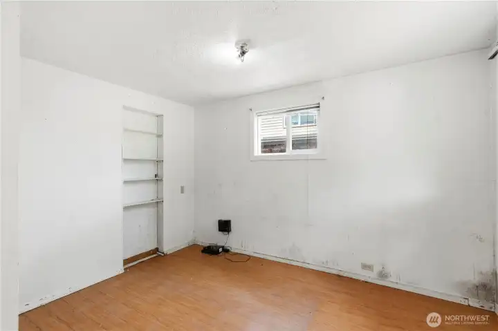 Bedroom #1 with built-in shelving space and laminate flooring.