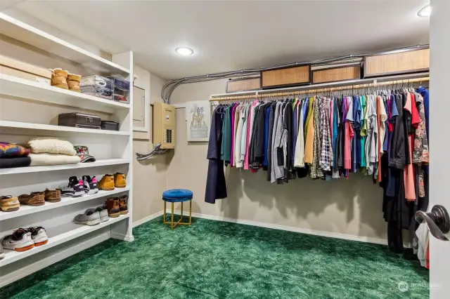 Primary bedroom's walk-in-closet includes built in shelving and electrical outlets for plugging in devices or accessories such as an iron.