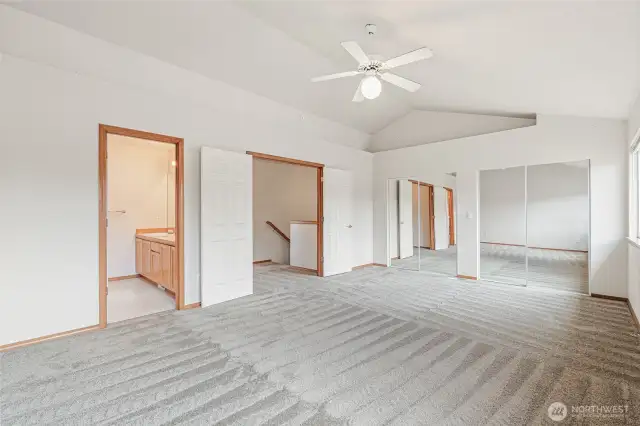Spacious primary bedroom. Primary 3/4 bath on left staircase seen thru the French doors, both which are opened. Wall to wall closet with mirrored sliding doors. Vaulted ceiling with high alcoves for creating your own oasis.