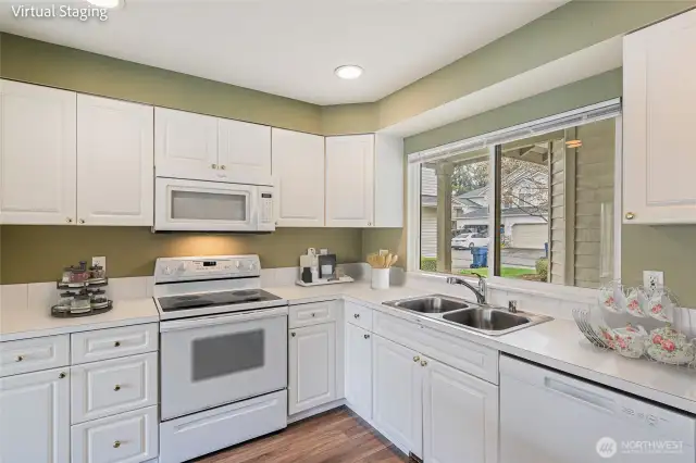 The kitchen. Double sink, dishwasher, refrigerator (just to the right, out of picture), range and oven, built in microwave. Window looks out to the front of the building, covered entry is just on the other side of the window.