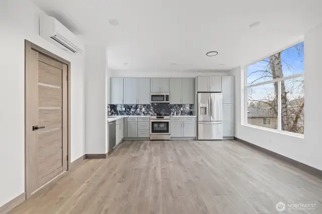 Kitchen view from living room and dining room with view of the kitchen showcases the lay out and high finishes you can expect in the newly constructed home at 8608 42nd Ave S, Seattle, WA 98118, built by the same builder."