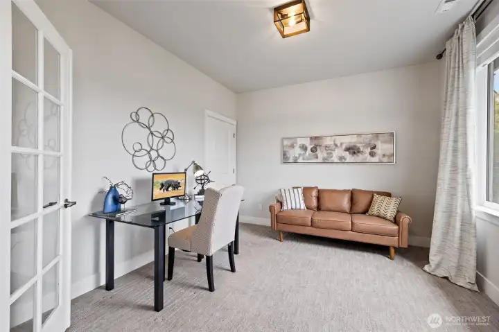 Elegant glass French doors open to a versatile space; ideal for office or fourth bedroom.