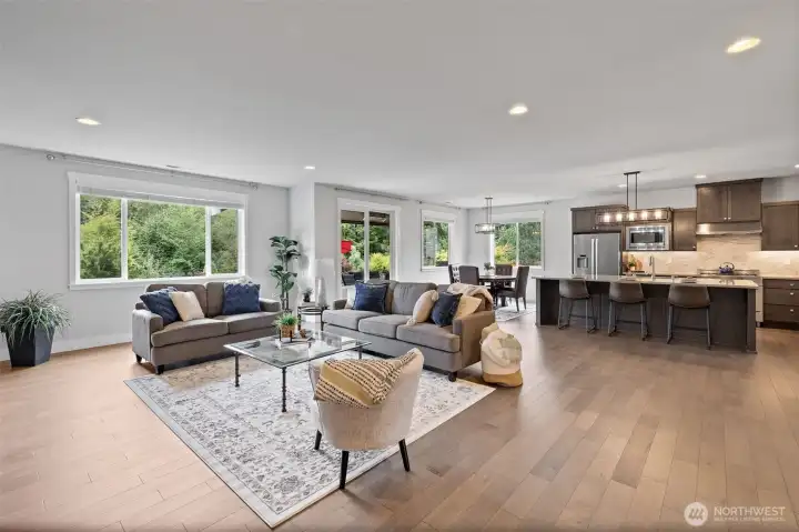 Great room flows seamlessly from gourmet kitchen providing a cozy and elegant gathering space with serene views of lush greenery through the picture window.