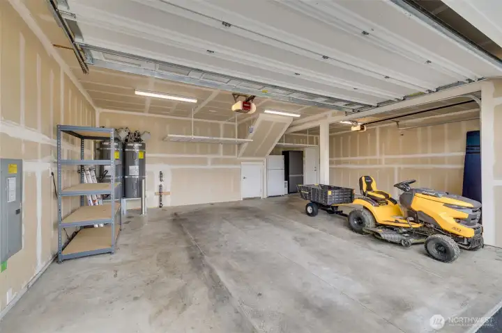 Spacious three-car garage with overhead storage and additional refrigerator for added convenience.