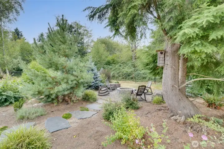 Additional cozy, wood-burning fire pit/seating area enhancing the beauty of this immaculate, park-like 1+ acre oasis.