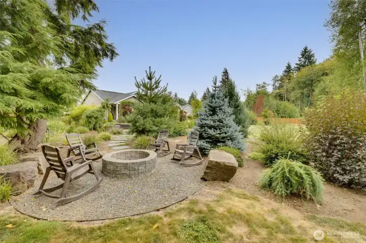 Additional cozy, wood-burning fire pit/seating area enhancing the beauty of this immaculate, park-like 1+ acre oasis. Year-round enjoyment.