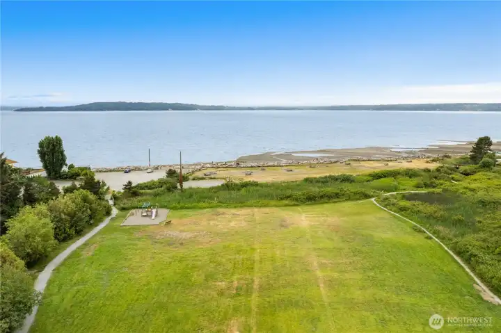 An aerial view of The Cove to show the lengthy beach, flat grassy space, play toy and more.