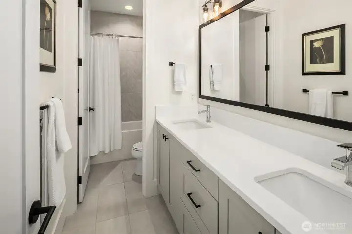 Shared full bath with double vanity and tile surround