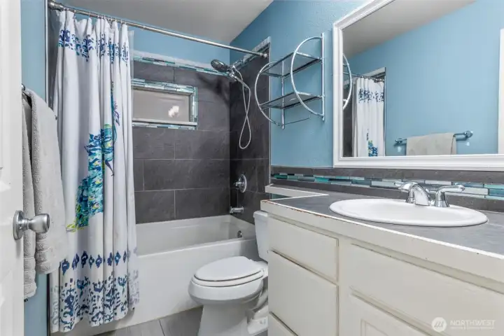 Attached primary bathroom with updated tile shower and flooring.
