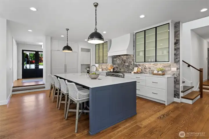 Kitchen with oversized quartz island, integrated Monogram appliance package including 48 in dual oven range, and 108 wine bottle Sommelier fridge
