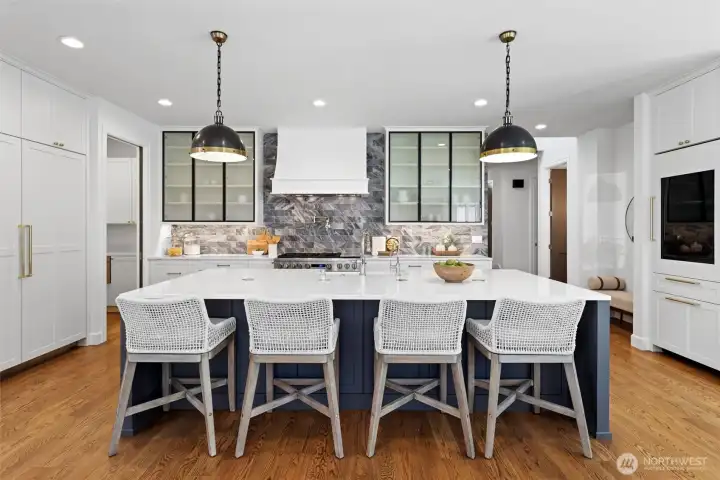 Kitchen with oversized quartz island, integrated Monogram appliance package including 48 in dual oven range, and 108 wine bottle Sommelier fridge