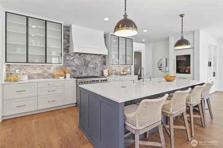 Kitchen with oversized quartz island, integrated Monogram appliance package including 48 in dual oven range, and 108 wine bottle Sommelier fridge