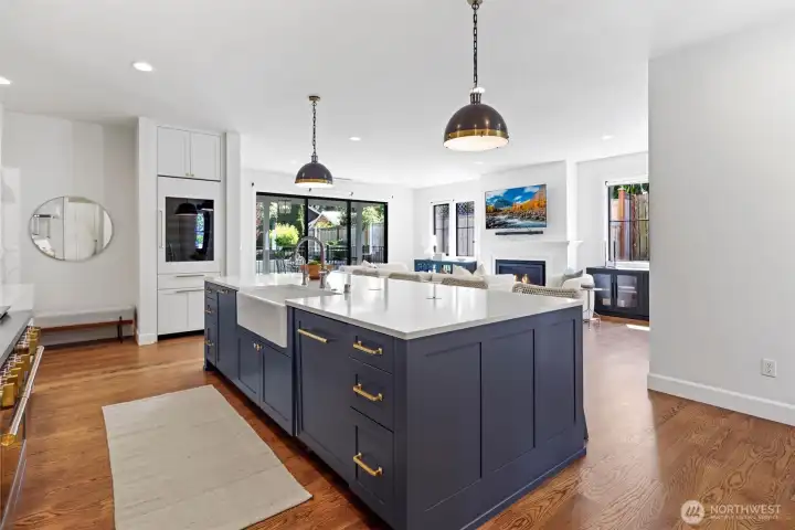 Kitchen with oversized quartz island, integrated Monogram appliance package including 48 in dual oven range, and 108 wine bottle Sommelier fridge
