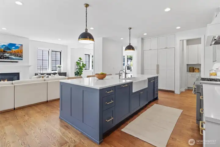 Kitchen with oversized quartz island, integrated Monogram appliance package including 48 in dual oven range, and 108 wine bottle Sommelier fridge