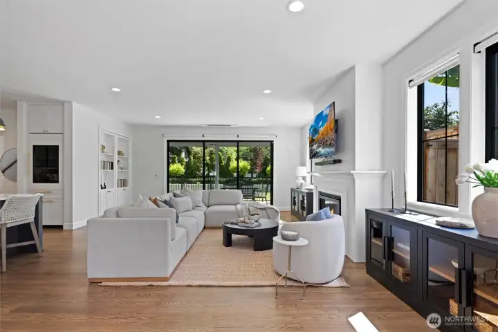 Main open-concept living space with seamless flow to Kitchen, Dining & Outdoor entertaining patio through Fleetwood sliding doors. Gas Fireplace. TV conveys with home.