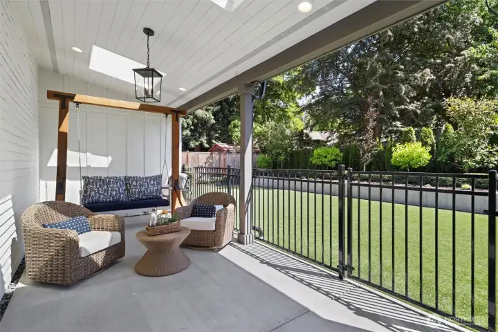 Backyard entertaining patio with skylights and curated light fixtures. Patio swing conveys with home