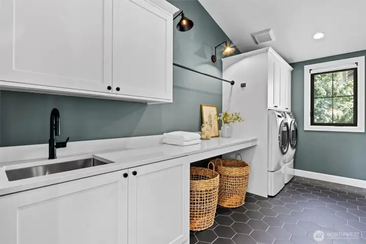 Large laundry space with side by side front load washer/dryer, utility sink, drying rack, and so much storage!