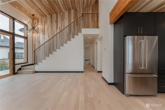 Stairs leading up to second floor primary bedrooms and hallway leading to den and main floor primary ensuite bedroom