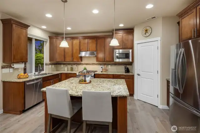 Nicely appointed kitchen features slab granite counters and a stainless appliance package