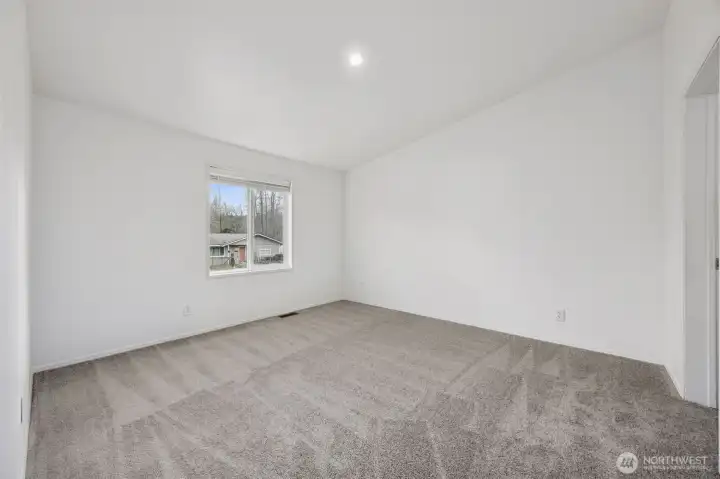 The primary suite is pleasantly surprising in all the right ways. Vaulted ceilings add volume, the mushroom-toned carpet keeps it comfortable, and the large window brings in plenty of light while the blinds are already handled for you. Overlooking the front yard, the room feels open without feeling exposed. It’s bigger than you expect, which is always a nice moment.