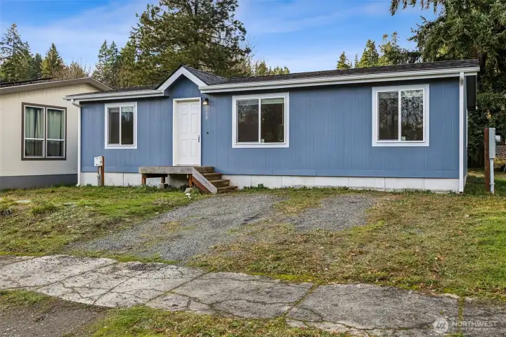 This view shows why this home lives more like a site-built than you might expect. The concrete foundation provides a solid base, the utilities are cleanly installed, and there’s extra parking space right out front for visitors. For a double-wide, these are meaningful upgrades that make a real difference in comfort, usability, and long-term value.