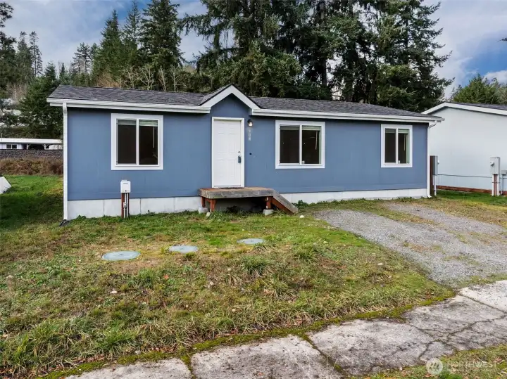 From this view, you can see how the layout works in your favor. There’s clear side access that sets up perfectly for a future gate and fenced backyard, and the gravel driveway comfortably fits two vehicles. The blue siding and crisp trim keep things fresh and modern, while the overall setup leaves room to customize as you go.