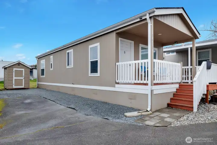 Front of home with long driveway and storage shed.