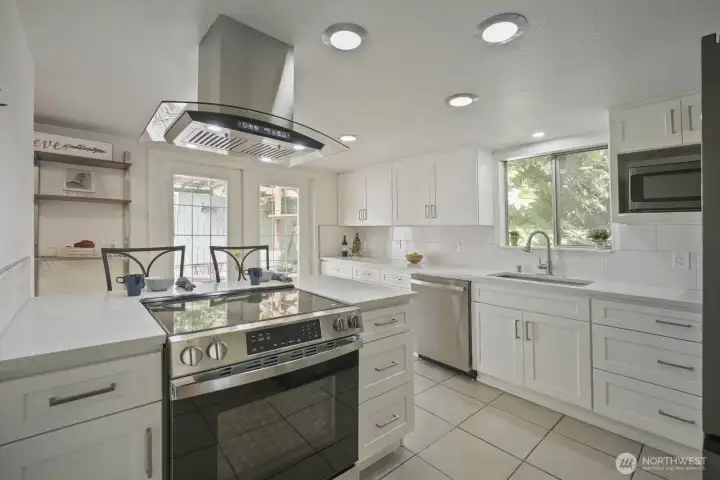 Freshly remodeled kitchen! Tile flooring, peninsula breakfast bar with drop in smooth top range, stainless draft fan & Quartz countertops. Great shelving & organizing station on back wall.  Also, notice the french doors to the back patio & yard