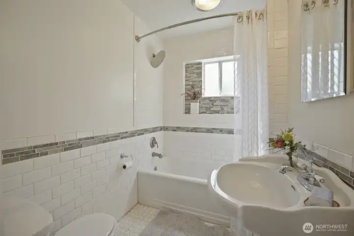 Full bath on main floor with intricate tiling work that surrounds the majority of the bathroom. Deep tub with rain showerhead, built in shelf & window for great ventilation & natural lighting