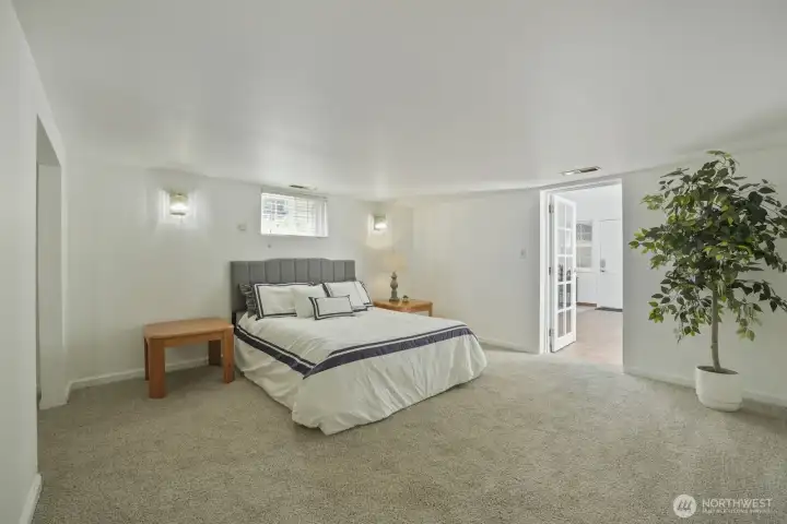 Heading down to the basement via carpeted stairs with handrail, entering into roughly 6'5" or so ceiling height, you'll find a super large bedroom with plush carpeting, window, sconce lighting & glass paneled door which leads to the atrium and 2nd full bath