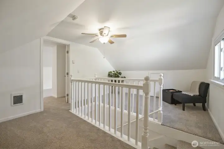 Headed up to the 2nd Story, to a large loft area with wood railings, ceiling fan and window.  Attic access on both sides of loft. This door leads to another vast bedroom