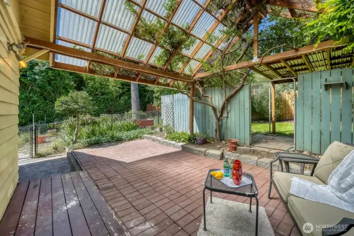 Off the kitchen, through the french doors, you'll find the little deck with brick extension patio, covered by an awesome, treated wood structure that has a high peak with plastic roofing to allow light through.  Lovely vine tree is interwoven into the patio cover. The cover then extends with a metal roof (right top of photo), into the rear backyard yard where you'll find fresh new grass