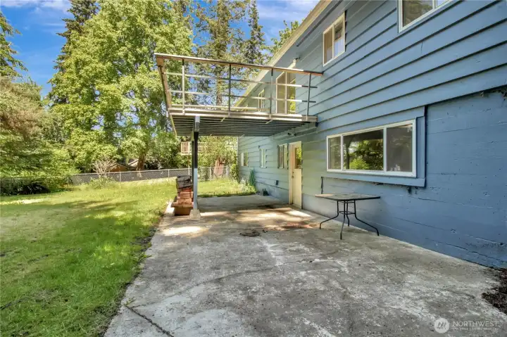 Back patio with door into the mud room and deck above Back patio with door into the mud room and deck above