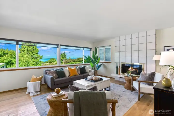 Spacious living room with fireplace and expansive windows showcasing territorial and water views