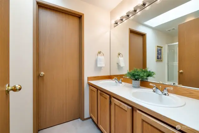 Primary ensuite bath has dual sinks, glass shower / tub,  walk-in closet