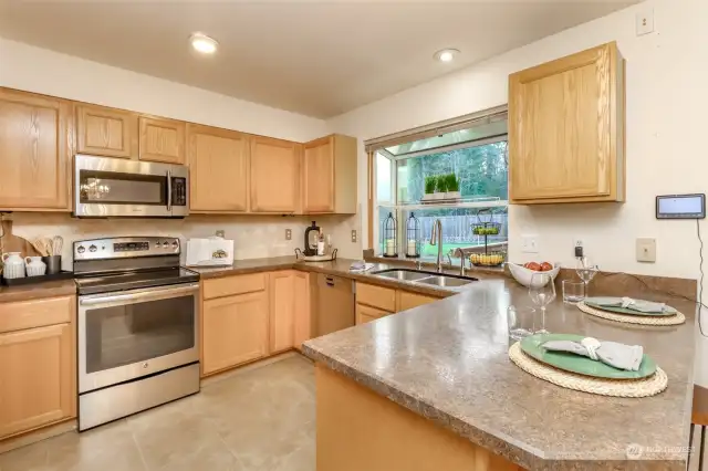 The kitchen designed for both functionality and style, offering an abundance of storage options to keep everything. A large garden window serves as the centerpiece, flooding the space with natural light and providing the perfect spot for growing herbs or enjoying a view of the outdoors