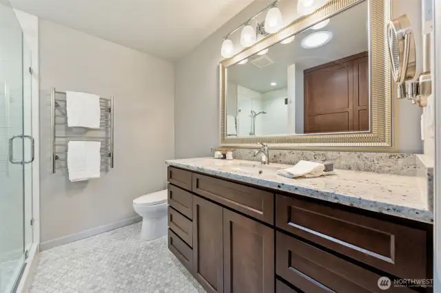 The spa-like Primary Suite bath features granite countertops, extended counter space, and Shaker-style cabinets for a clean, timeless look. Ceramic tile flooring, updated fixtures, and a sleek glass shower add to the serene and functional design.