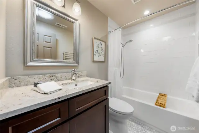 The Main Bath is centrally located near both bedrooms and features a granite counters, sleek tile surround, and a soaking tub with shower.  The Seller has gone the extra mile throughout this home, providing an insulated wall for comfort and quiet. The recessed medicine cabinet is concealed behind the mirror for sleek, functional storage.