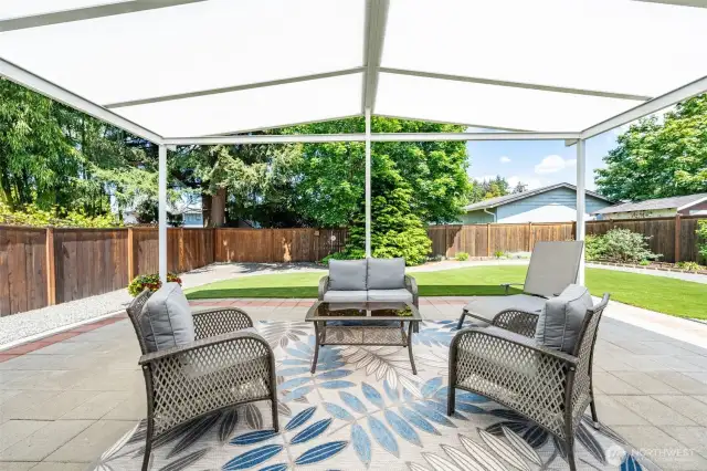 Unwind in style under this expansive covered patio—an inviting outdoor living space perfect for morning coffee, evening gatherings, or relaxing in the shade while overlooking the beautifully landscaped backyard.