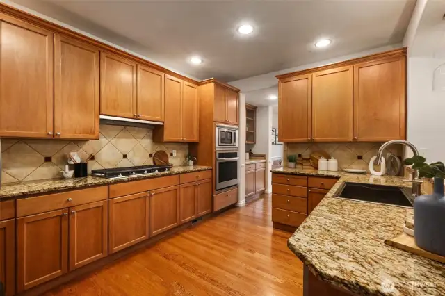 This beautiful chef's kitchen offers matching stainless steel appliances with a built-in microwave and a new oven (2025), warm wood cabinetry, granite countertops, and a timeless tile backsplash—blending function and style in the heart of the home. The butler’s pantry offers a perfect balance of style and utility, with tiled countertops for serving or prep, and upper glass-front cabinets ideal for displaying your favorite tableware.