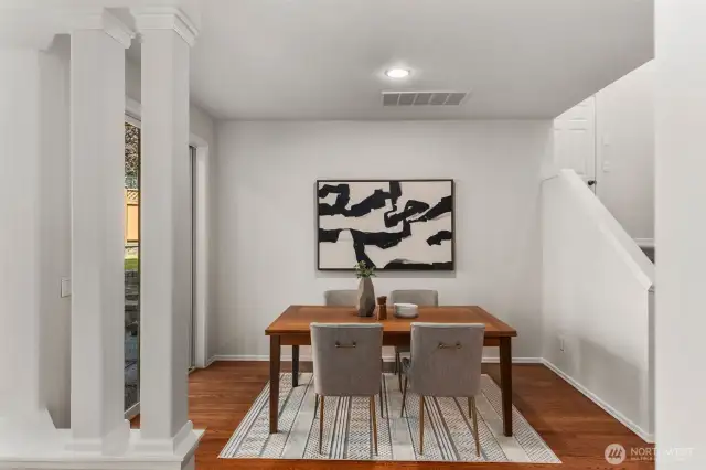 This bright and inviting dining area features the continued hardwood flooring, soft white wall color, and recessed lighting throughout the home. Open stairs to the second floor add to the home's airy feel and sense of connection.