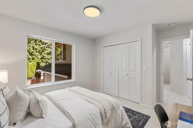 The first guest bedroom offers a peaceful retreat with soft new carpeting underfoot, a wide closet with double doors, and a large window that brings in gentle natural light.