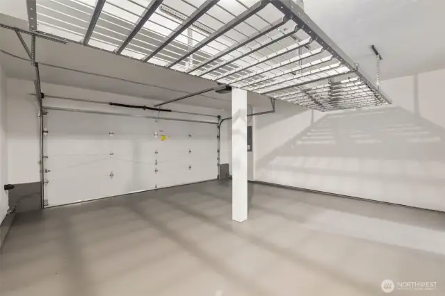 This spacious two-car garage features freshly primed and painted walls and flooring, creating a clean, finished look. A ceiling-mounted storage rack (installed in 2020) adds convenient overhead organization, while the automatic garage door opener (new in 2019) brings modern ease to your daily routine.  The home's two-car garage is located at the rear and backs to a privately owned wooded lot—offering both easy access and a peaceful, tucked-away setting.