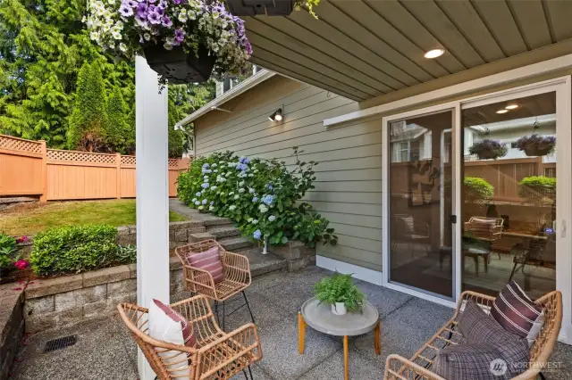 The covered patio just off the informal dining area is the perfect place to unwind, overlooking a tidy lawn and beautifully maintained tiered garden beds.