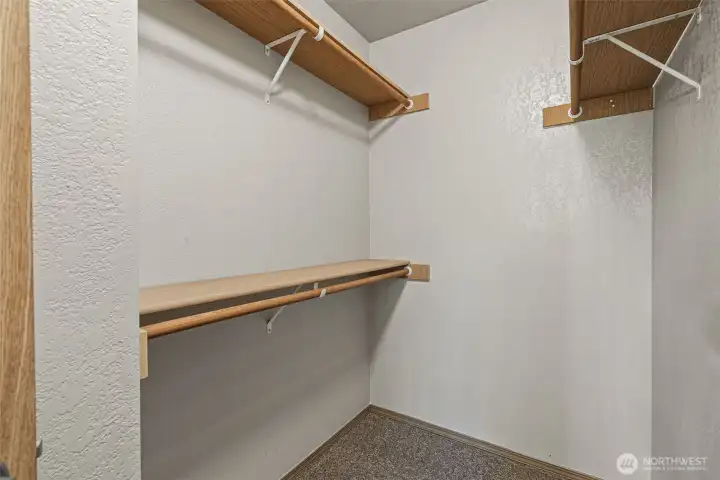 Walk-in closet features wood shelves and bars
