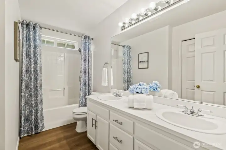 Upstairs hall bath has dual sinks, new flooring, and tub with shower.