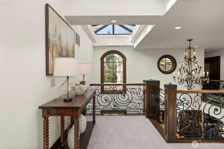 Light-filled upper landing featuring a skylight, custom wrought-iron railing, and refined architectural details.